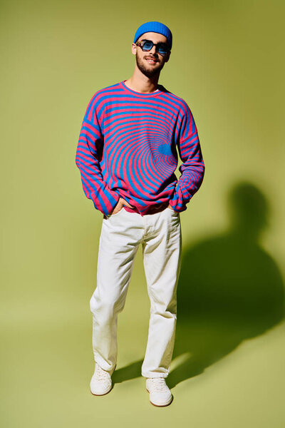 A fashionable young man poses confidently in stylish vibrant attire with trendy sunglasses.