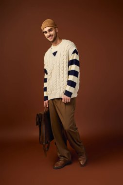 Kendine güveni tam bir genç adam. Stüdyoda örülmüş bir bereyle şık kış kıyafetlerini modelliyor..