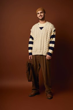 Şık bir genç adam canlı bir arkaplanı olan bir stüdyoda kendine güvenerek duruyor..