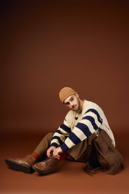 Yakışıklı bir genç, stüdyoda otururken eşsiz moda anlayışını sergiliyor..