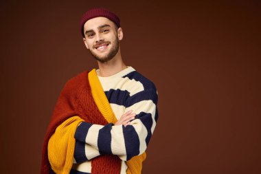 Yakışıklı genç adam kendine has tarzını canlı bir elbiseyle kahverengi bir arkaplanda sergiliyor..