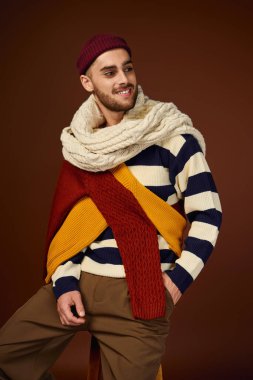 Şık bir genç adam, moda anlayışını örgü bir bere ve kalın kış katmanları ile sergiliyor..