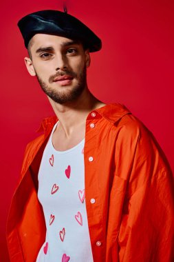 A young man displays his unique style in a studio with a red backdrop, wearing a heart tee. clipart