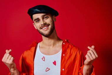 Romantik bir genç adam benzersiz moda yeteneğini kırmızı renklerle dolu bir stüdyo ortamında sergiliyor..
