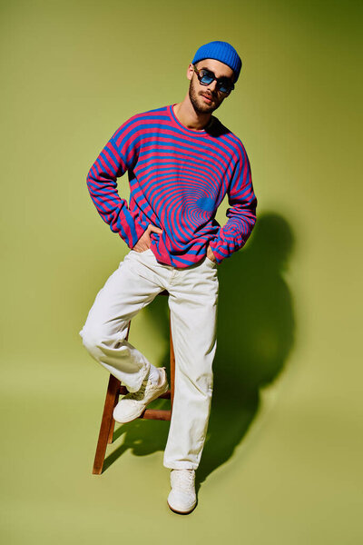 A young man poses with style against a bright green backdrop, exhibiting contemporary fashion flair.