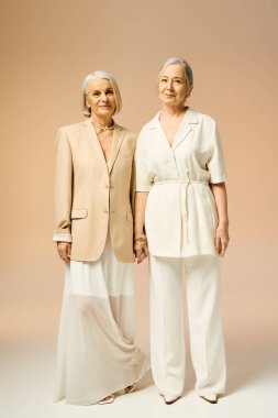 İki modaya uygun kadın, şık elbiseleriyle romantik ve gururlu bir şekilde birbirlerine yakın dururlar..