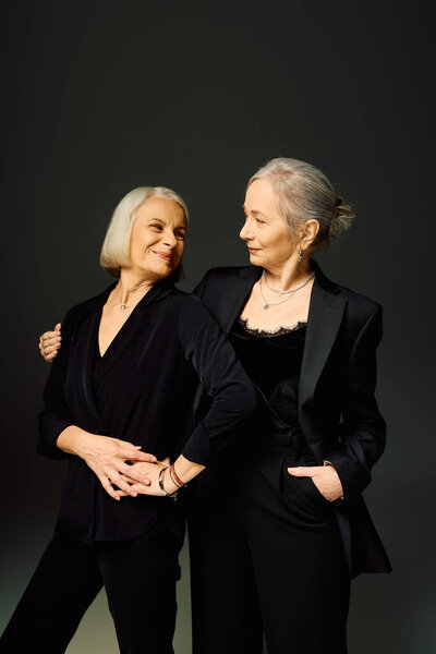 Две модные женщины выражают любовь и связь, изящно позируя в шикарных нарядах.