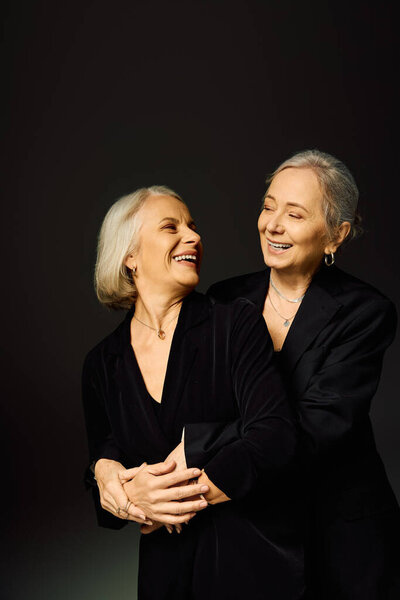 Две зрелые женщины обнимаются с радостью, демонстрируя любовь и связь в шикарной атмосфере.