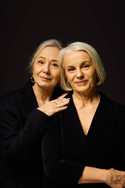 Две элегантные женщины разделяют сердечные объятия, демонстрируя свою любовь и стиль в шикарной обстановке.