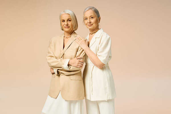 Two fashionable women share a loving moment, radiating joy and confidence in their stylish outfits.