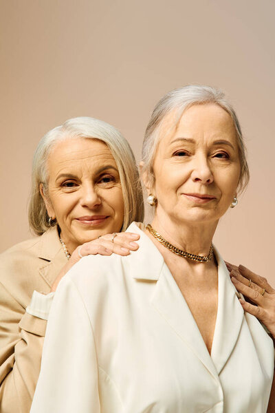 Две зрелые женщины разделяют любящий момент, подчеркивая свой стиль и связь в современной обстановке.