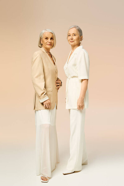 Two stylish mature women display their romance and bond through chic outfits and confident poses.