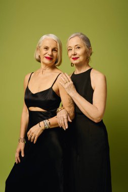 İki şık kadın, canlı yeşil bir zemine karşı sevgi dolu bir anı paylaşıyor..