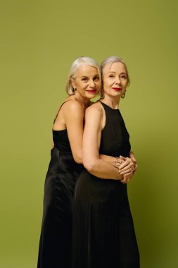 İki olgun kadın birbirlerine sıcak bir şekilde sarılırken, aynı zamanda zarif ve sevgi dolu tavırlarını sergiliyorlar..