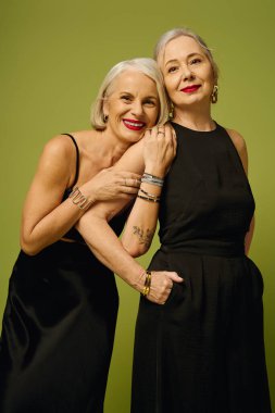 İki olgun kadın, şık kıyafetlerini ve güçlü bağlarını sergileyerek, sevgi dolu bir anı paylaşıyor..