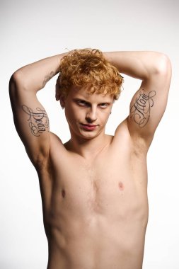Şık bir genç adam kendine güvenerek poz verir, dövmelerini ve çekiciliğini gösterir..