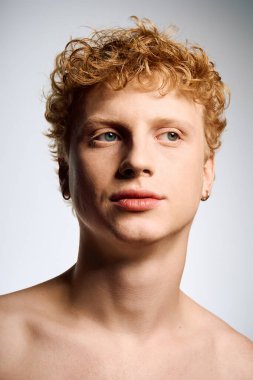 Genç bir adam modaya uygun kıvırcıklarıyla ve çarpıcı özellikleriyle gösteriş yapıyor, zahmetsizce dikkat çekiyor..