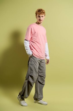 Şık bir genç adam yeşil duvarın karşısında gelişigüzel poz veriyor..