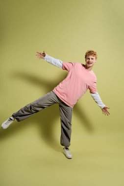 Modayı takip eden genç bir adam eğlenceli bir poz verir, modaya uygun kıyafetlerini ve neşeli tavırlarını sergiler..