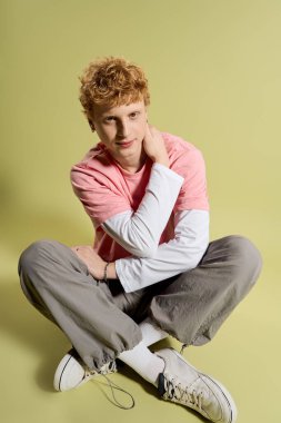 Genç ve yakışıklı bir adam şık bir kıyafetle bağdaş kurup şık bir hava veriyor..