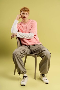 Tarz sahibi genç bir adam sakin yeşil bir zemine karşı şık bir elbise içinde poz veriyor..