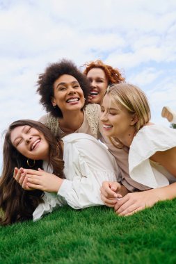 Four stylish friends laugh together on a lush lawn, celebrating the joy of spring. clipart