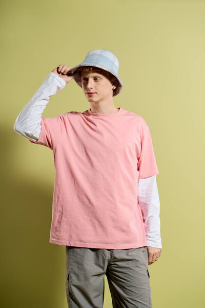 A stylish young man poses confidently in a pink shirt and bucket hat.