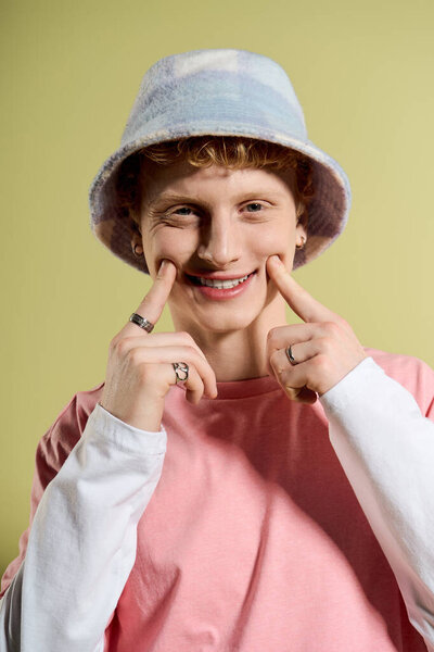 Cheerful young man in a fashionable outfit playfully poses and lights up the space with joy.