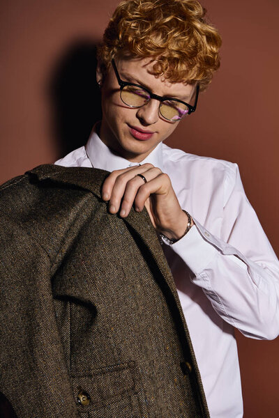 Красивый молодой человек в стильном наряде аккуратно настраивает свою куртку, демонстрируя легкую моду.