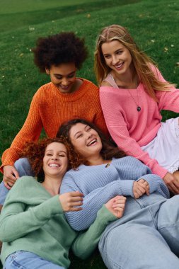 Four women showcase their chic spring looks while enjoying a sunny day outdoors in the park. clipart