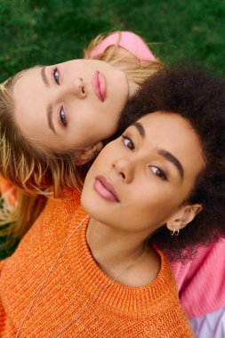 İki zarif kadın güzel yeşil bir parkta birlikte poz veriyor, özgüven ve tarz yayıyorlar..