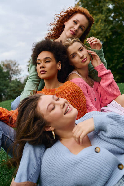 Четыре стильных друга греются на солнце в парке, излучая радость в своих ярких нарядах.