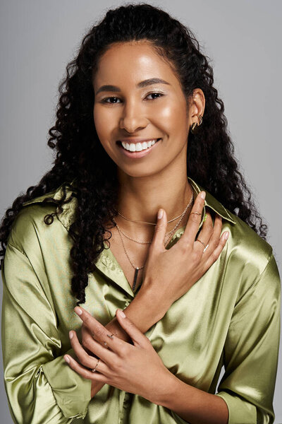 African american woman gracefully showcases her fashionable jewellery while smiling confidently.