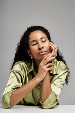 Kendine güvenen bir Afrikalı Amerikalı kadın şık kıyafetlerini ve mücevherlerini göstererek düşünceli bir şekilde poz veriyor..