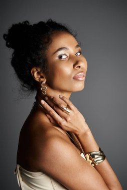 An elegant African American woman displays her chic outfit and beautiful jewelry in a calm setting. clipart