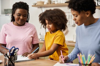 Üç aile ferdi evde yaratıcı bir etkinliğe katılıyor, kahkaha ve sevgiyi paylaşıyorlar..