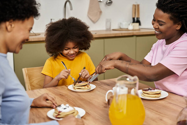 A loving family enjoys a delightful breakfast, sharing laughter and pancakes together.