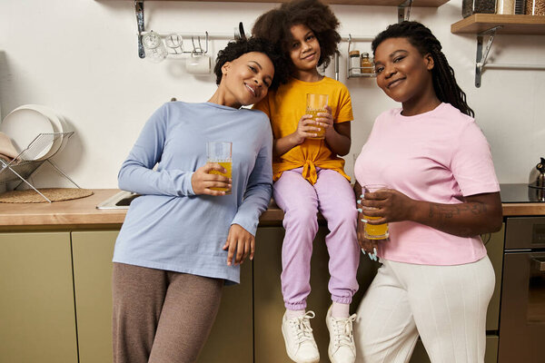 Три радостных члена семьи связываются и делятся напитками на теплой кухне, улыбаясь вместе.