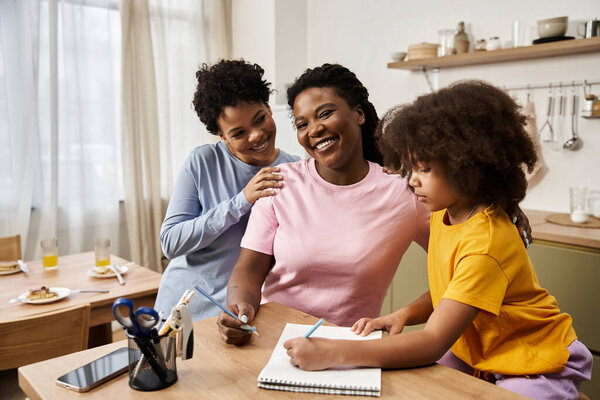 Смех наполняет воздух, когда трое членов семьи наслаждаются творческим временем вместе на своей кухне.