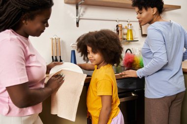 İki anne ve kızı renkli mutfaklarında bulaşık yıkarken mutlu mesut kaynaşıyorlar..