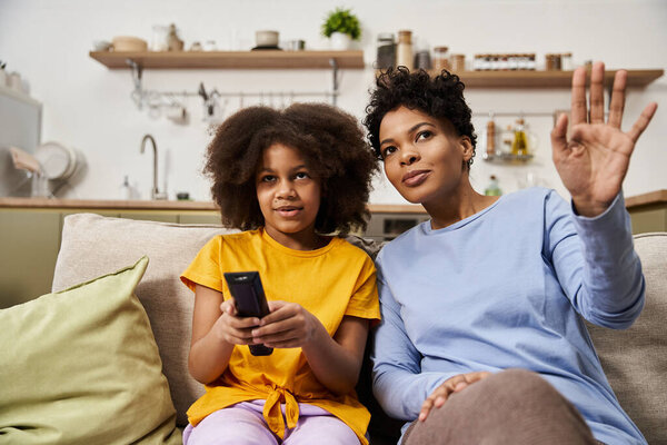 A mother and daughter share a delightful afternoon at home while watching television together.