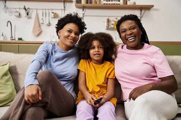 Три члена семьи разделяют смех и тепло, наслаждаясь временем в уютной обстановке.