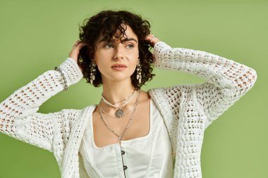 Güzel bukleli bir kadın zarif mücevherler ve şık elbiseler sergiliyor..