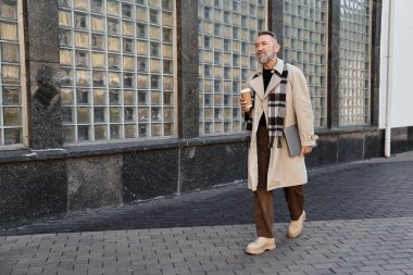 Yakışıklı bir son sınıf öğrencisi modaya uygun giyinmiş modern bir şehir manzarasında geziniyor..