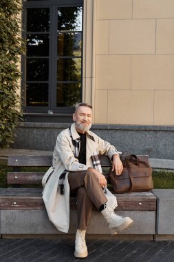 Yakışıklı bir son sınıf öğrencisi, son moda kıyafetleriyle parktaki bankta dinlenmek için biraz zaman ayırır..