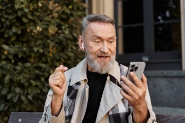 A fashionable senior man engages in a spirited discussion on his smartphone. clipart