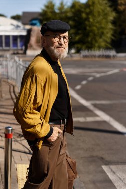 Şık, kıdemli bir adam canlı bir şehir manzarasında, modaya uygun kıyafetlerini sergileyerek rahatça dolaşır..