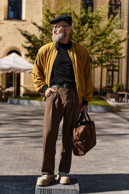 Şık bir kıdemli adam moda eğilimlerini yansıtan şık bir kıyafetle şehirde dolaşıyor..