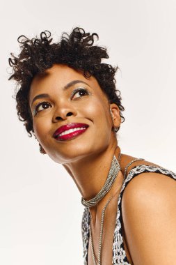 Çekici bir Afrikalı Amerikalı kadın, modaya uygun tarzını ve takılarını sergileyerek kendine güvenerek poz veriyor..