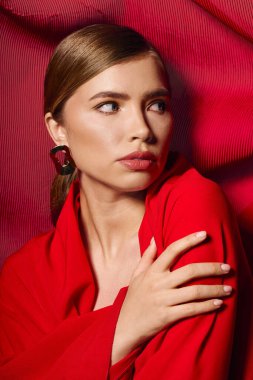 Canlı kırmızı kumaş zarif bir poz ve şık bir kıyafet sergileyen zarif genç bayanı tamamlıyor..